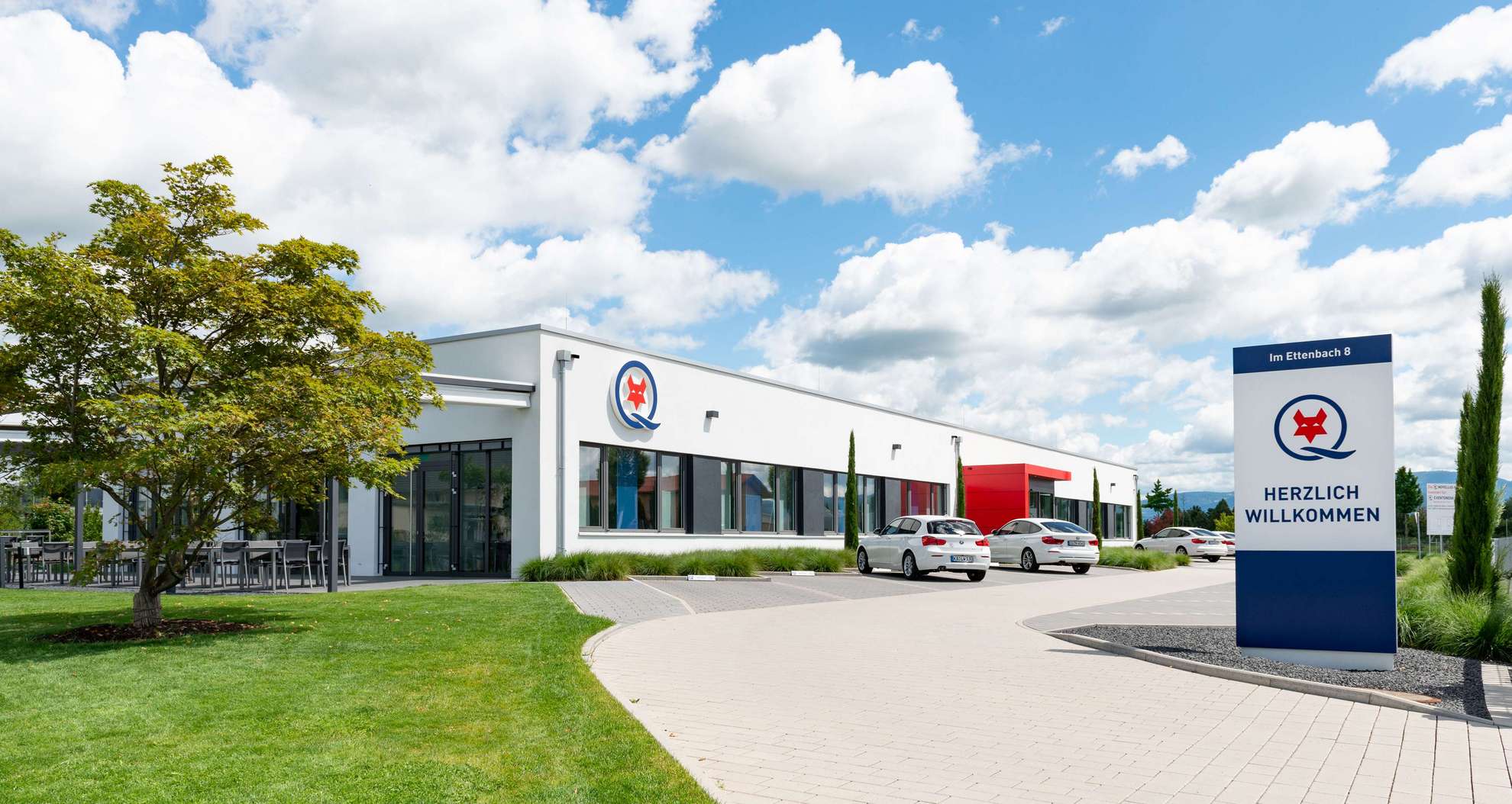 Gebäude Q-FOX® Admin Center mit Hofeinfahrt und Parkplatz